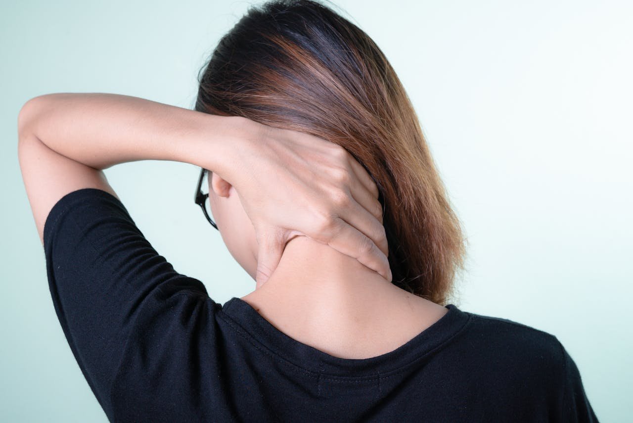 Woman holding the back of her neck in discomfort